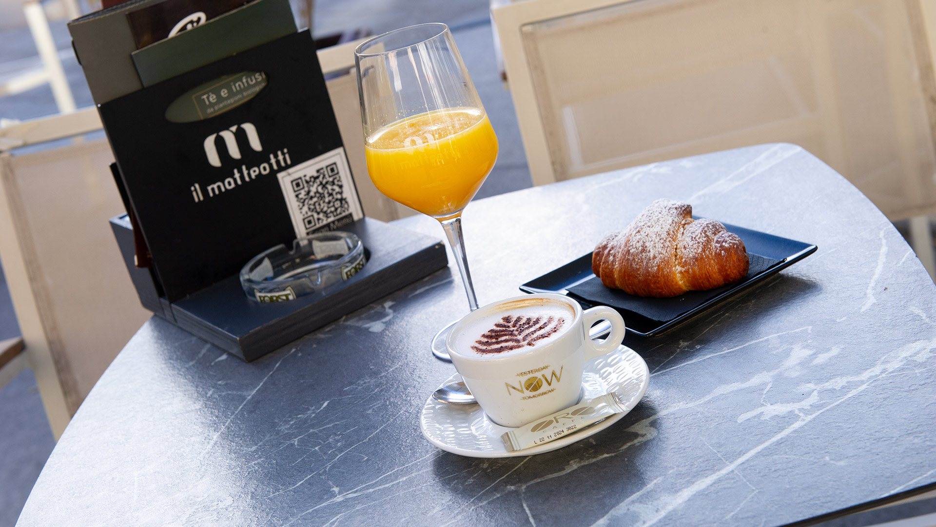 Una gustosa colazione all'italiana: caffè macchiato, succo d'arancia e brioche